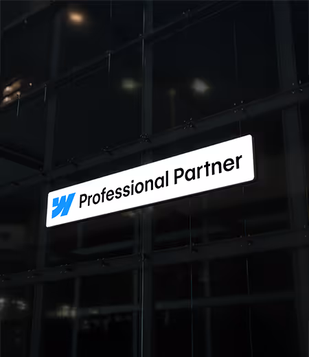 Webflow mavi logosu ve 'Professional Partner' yazısı bulunan ışıklı tabelanın gece dış cephe cama asılı hali.