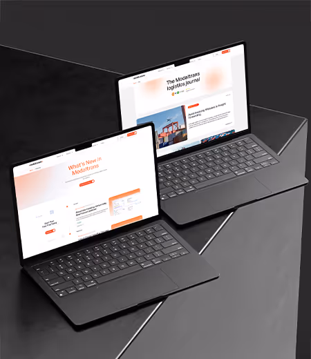 İki dizüstü bilgisayar, siyah bir yüzey üzerinde açılmış ve lojistik sektörüne dair haberler ve güncellemeler içeren web siteleri gösteriyor.