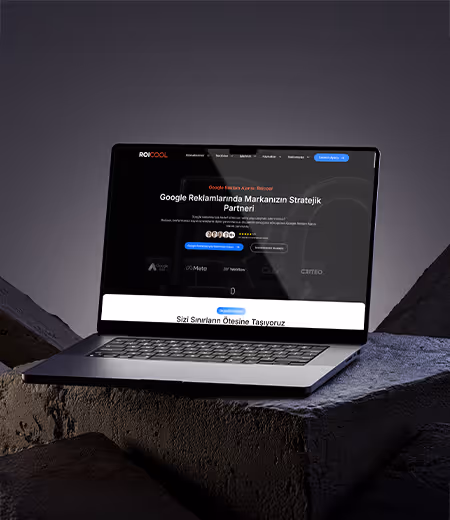 Karanlık arka planda taş üzerine yerleştirilmiş dizüstü bilgisayar ekranında Google reklam yönetimi hizmetleri sunan web sitesi görseli.