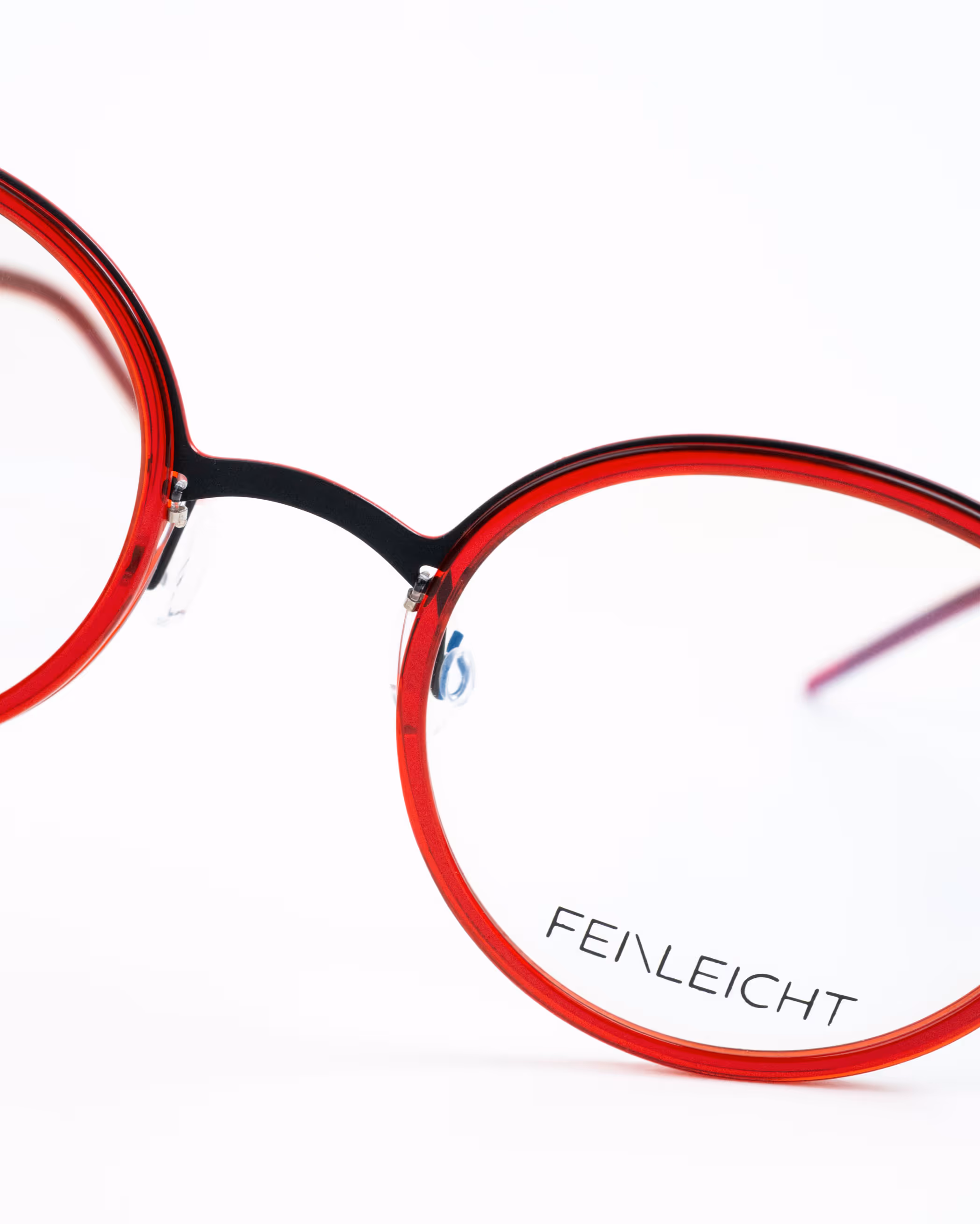 Feinleicht Titanbrille in Schwarz mit roten Bio-Acetat-Glasfassungen – filigranes Design trifft auf markante Farbkontraste.