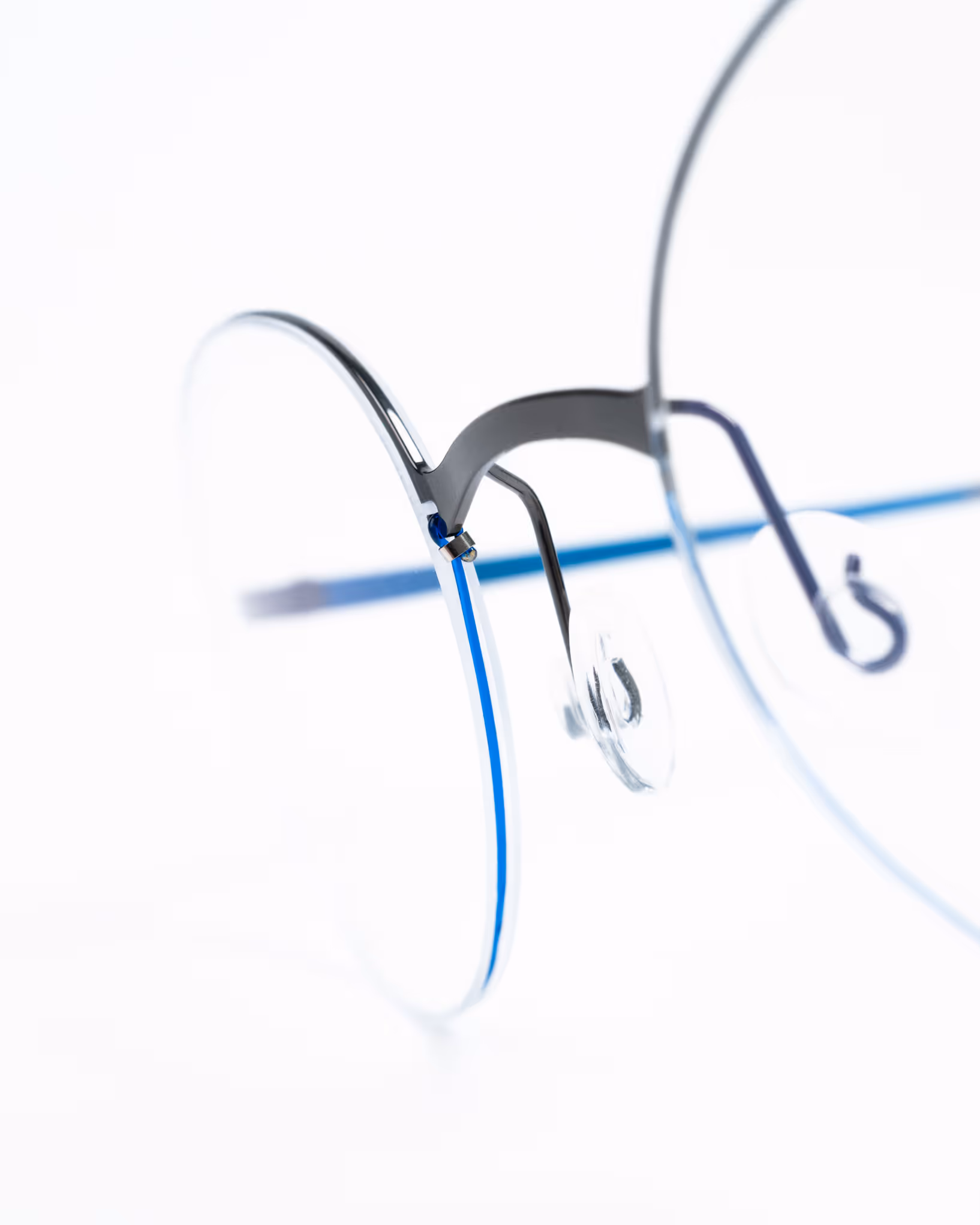 Detailaufnahme einer blau-schwarzen Feinleicht Brille mit klarem, modernem Design vor weißem Hintergrund.