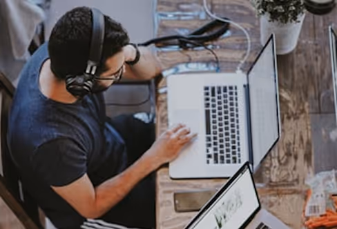 Support agent using VideoEngager on a laptop with headset and multiple screens.