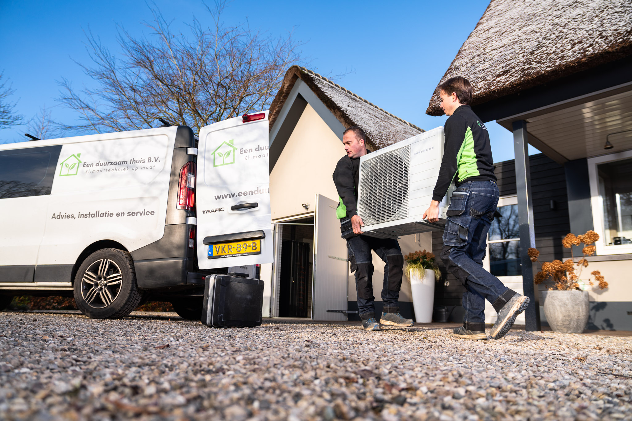 Jeroen en Niels tillen hier een warmtepomp voor installatie uit de werkbus