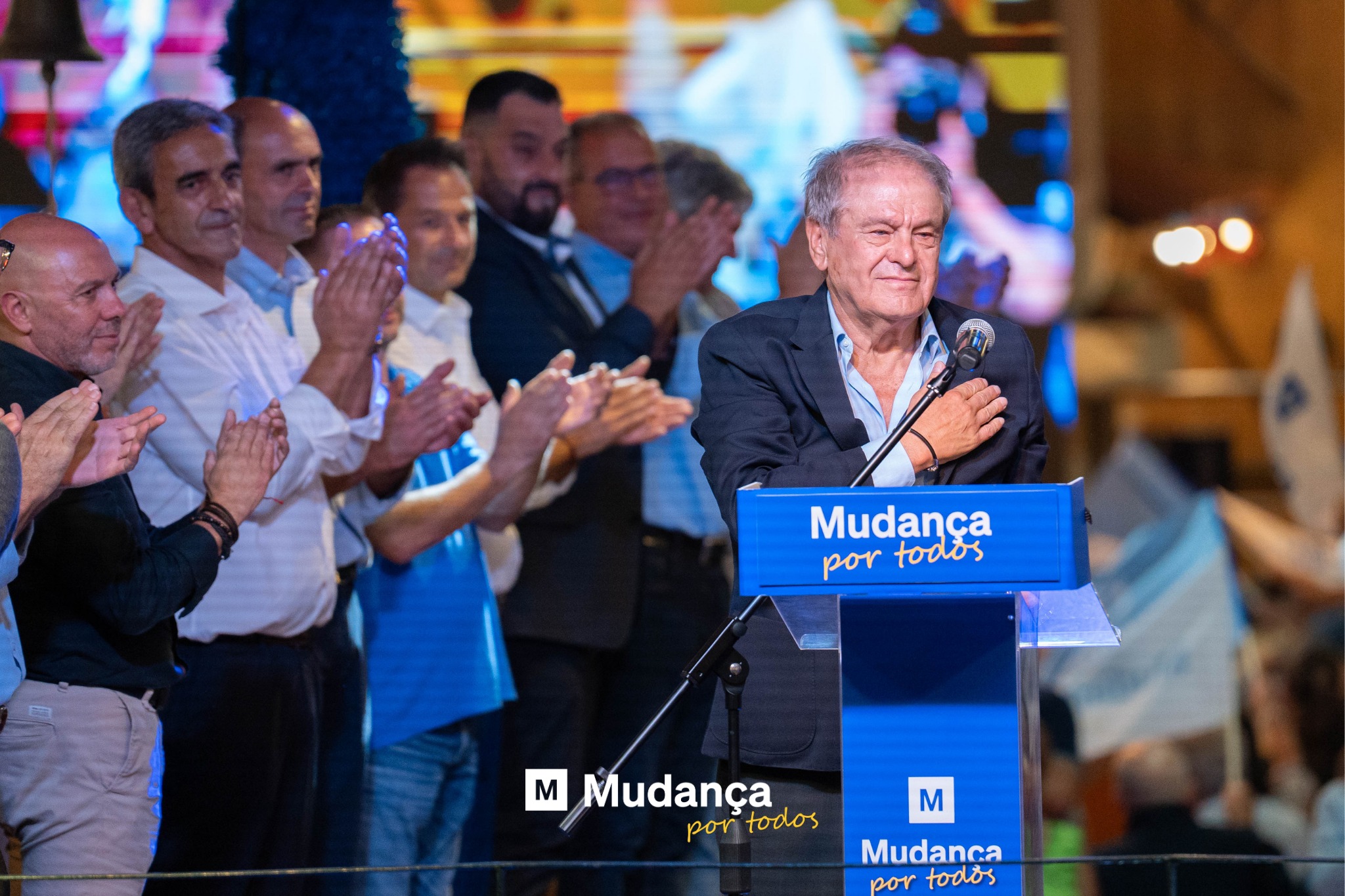 Pode ser uma imagem de 5 pessoas, sala de imprensa, multidão e a texto que diz "Mudança portodos por todos M M Mudança por portodos todos M Mudanca bor todos"