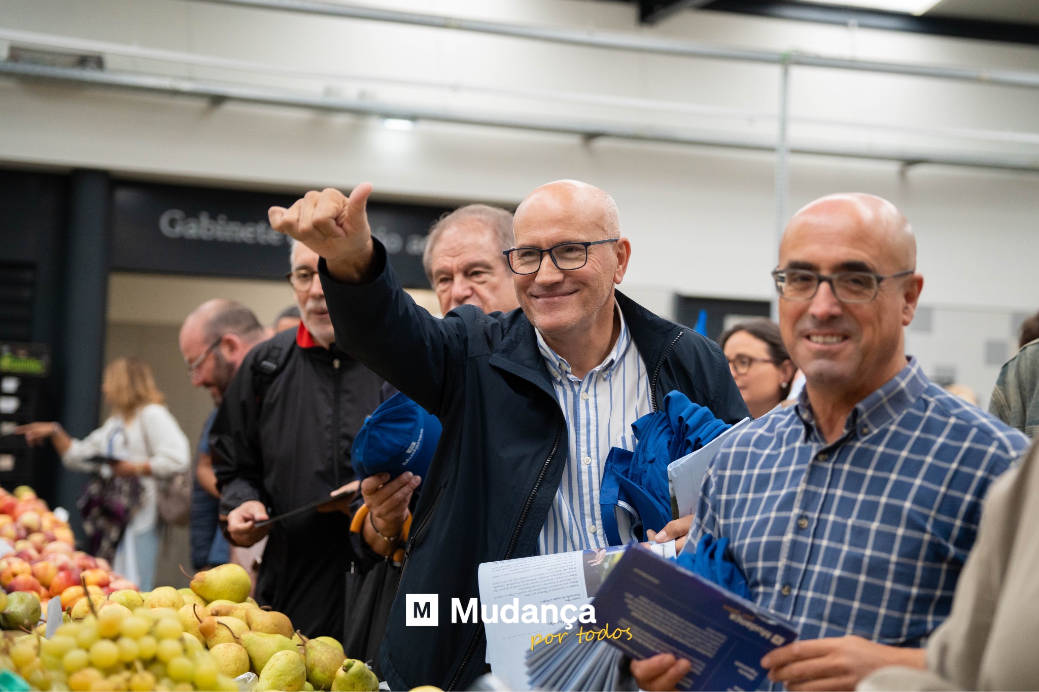 Pode ser uma imagem de 4 pessoas, fruta, multidão e a texto que diz "M Mudança portodos or todos"