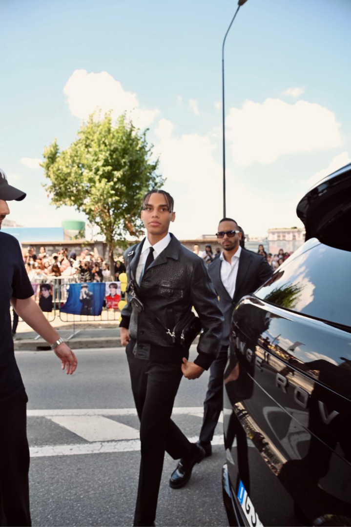 A man walking around a luxury SUV with his lifestyle liaisons around him