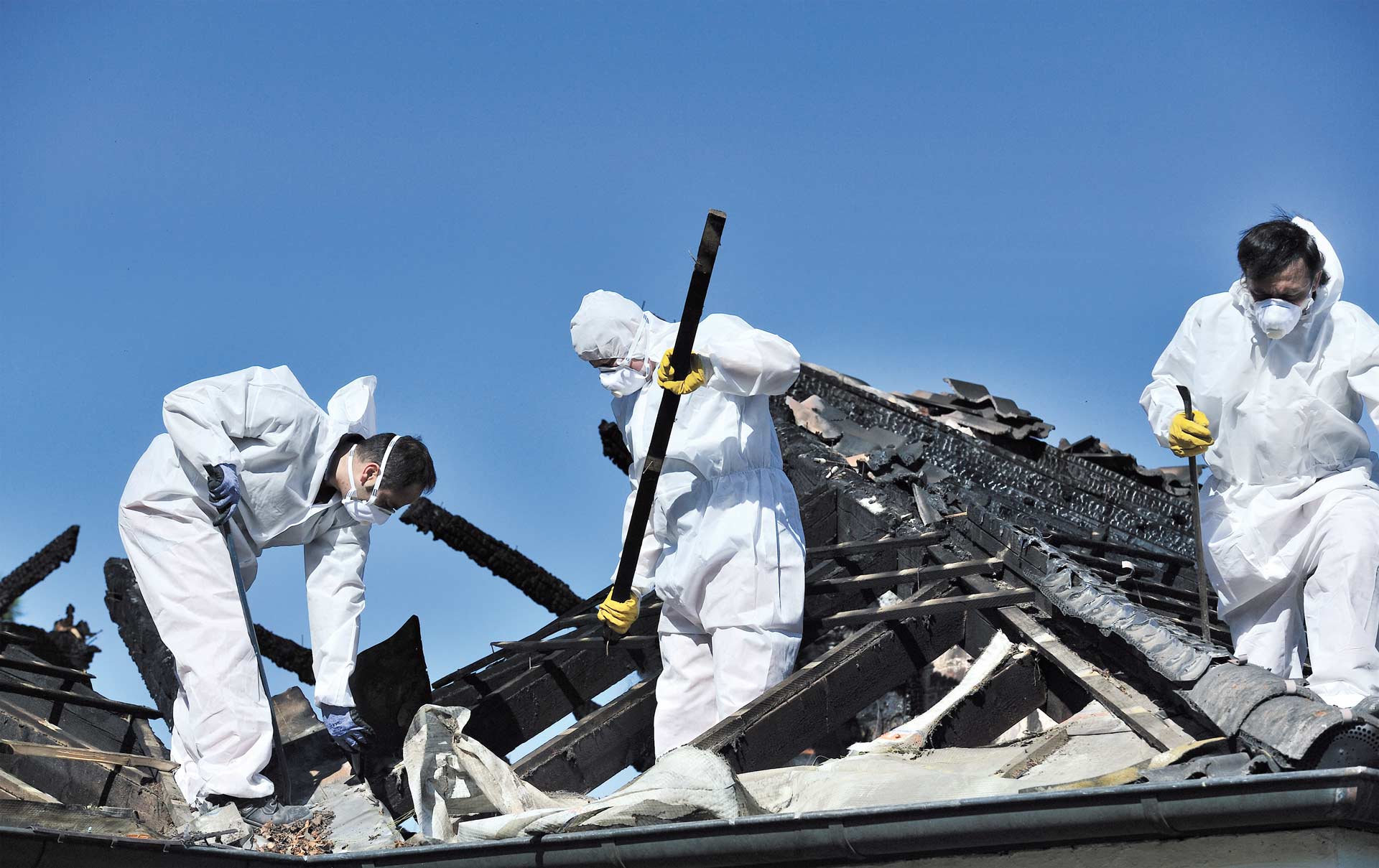 people cleaning up a burned roof