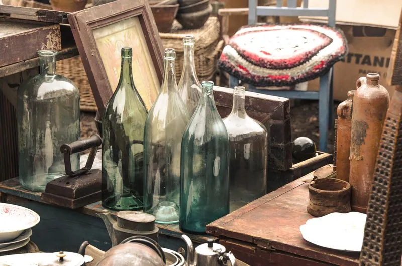Vieilles bouteilles en verre et objets anciens disposés lors d’un débarras de succession.