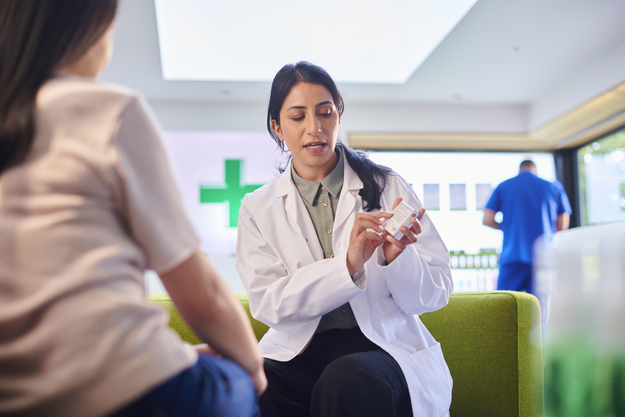A female pharmacist explains details of a medication to a female patient.