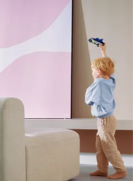 Young child playing indoors, holding a toy car up in the air.