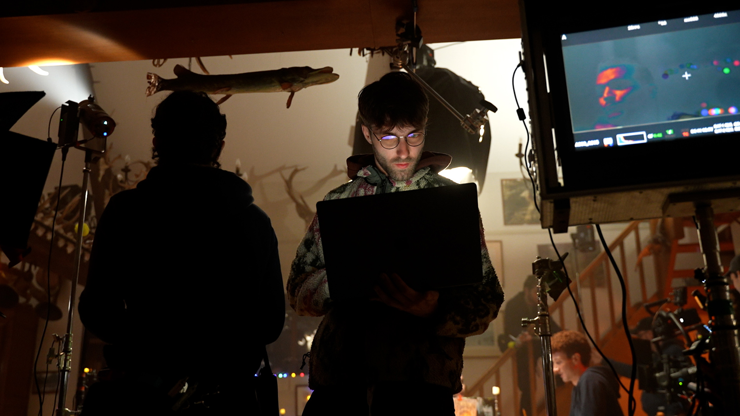 Mathis Capitaine concentré sur son ordinateur, debout au milieu d'un plateau de tournage