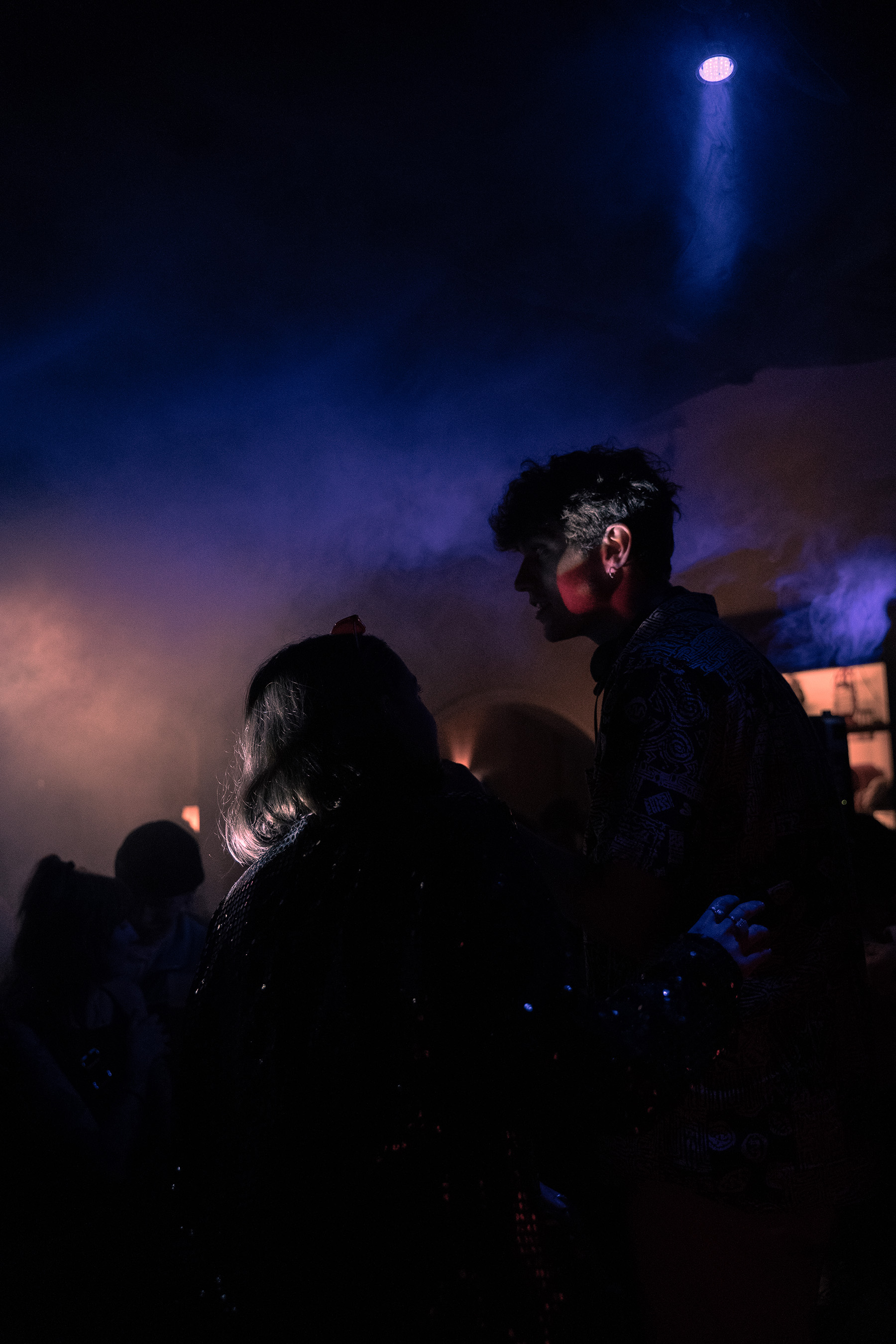 Deux personnes qui discutent dans soirée techno dans une ambiance orange et bleutée. Projet Symbiose