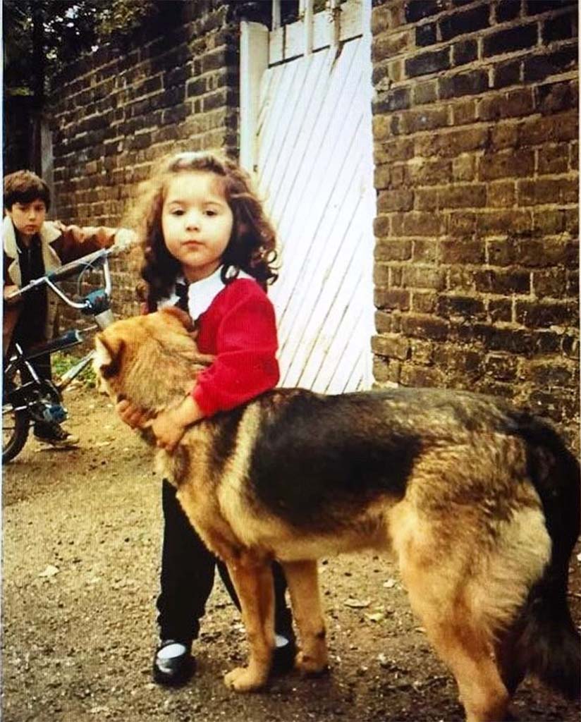 Jade as a child hugging a German Shepherd in the street