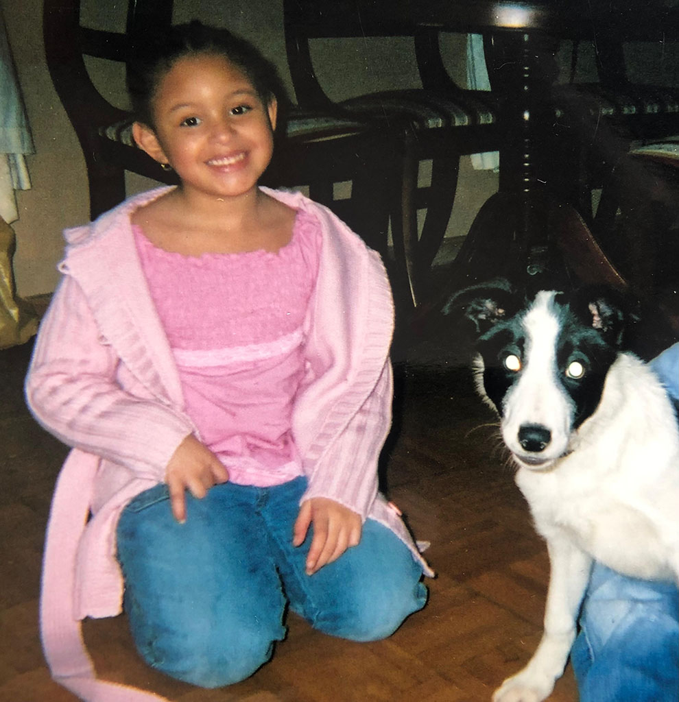 Courtney as a child sitting next to a dog at home