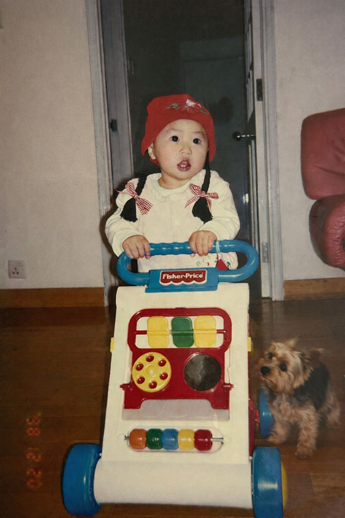 Rachel as a child pushing a toy next to a dog at home