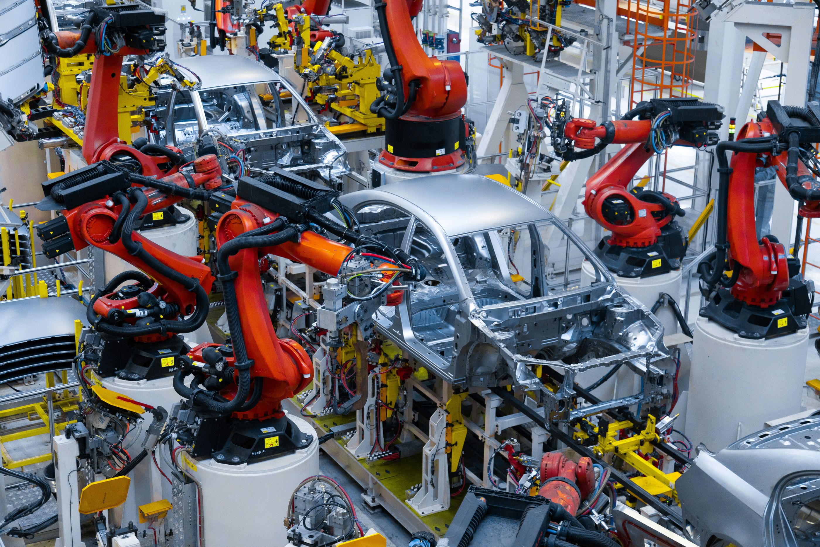 Assembly line with multiple robotic arms building car frames in an advanced automotive manufacturing facility.


