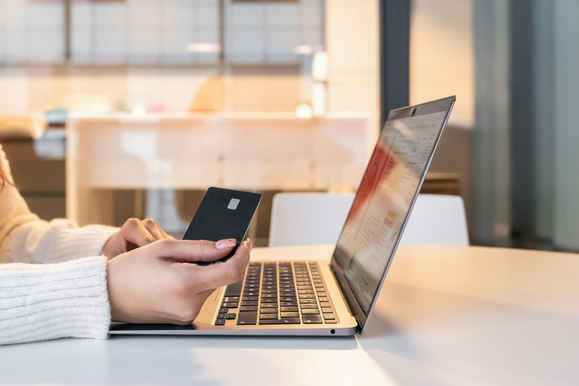 Person holding a credit card in front of a laptop