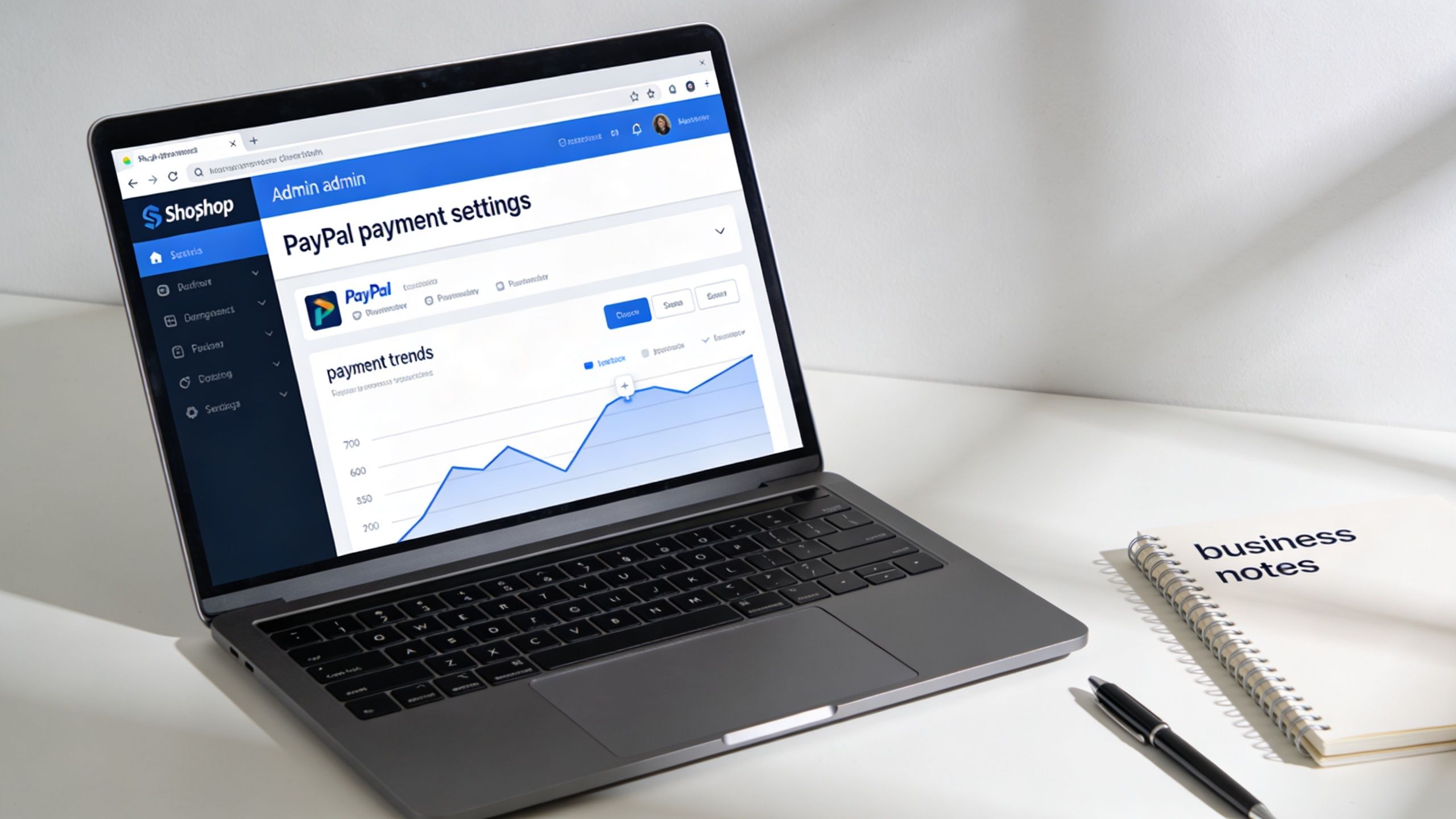 A modern laptop on a white desk displaying PayPal payment settings in an admin dashboard interface.
