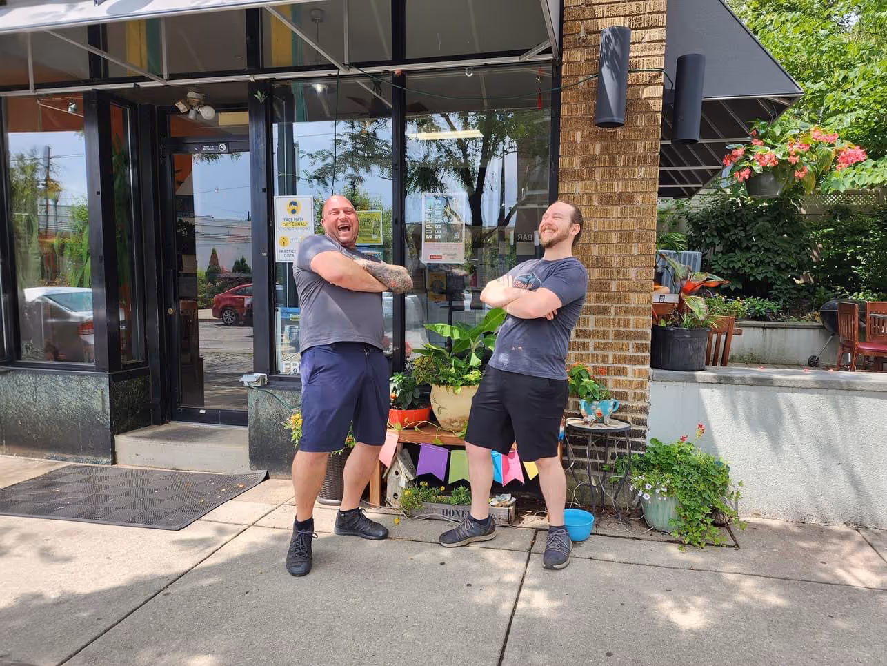 Two men standing outside a store, laughing.