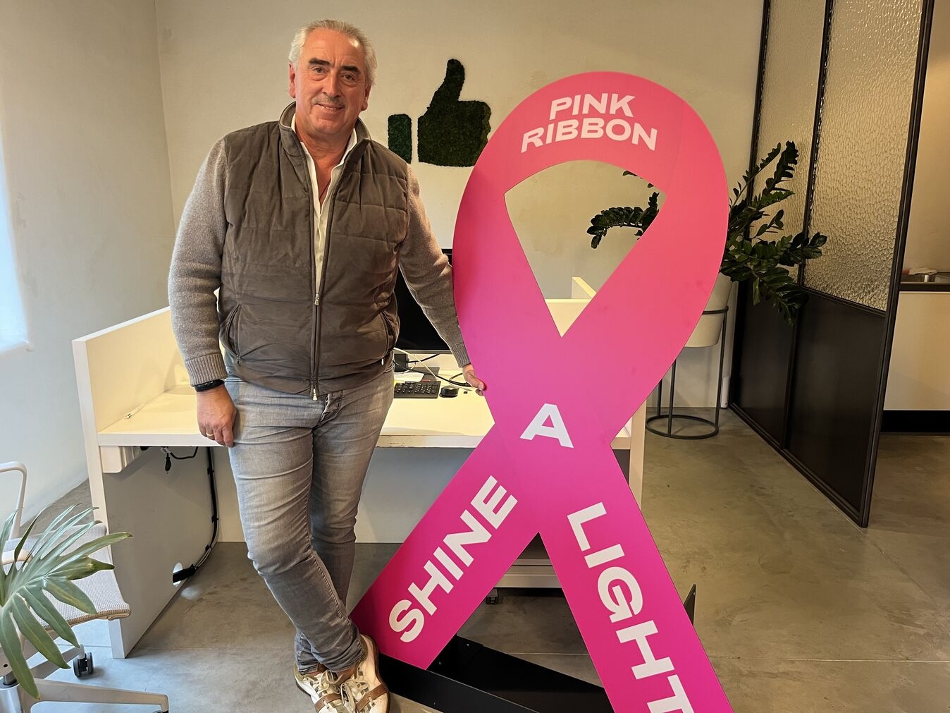 Aimé Van Hecke poseert met een grote versie van het Pink Ribbon Shine A Light lintje 2025.