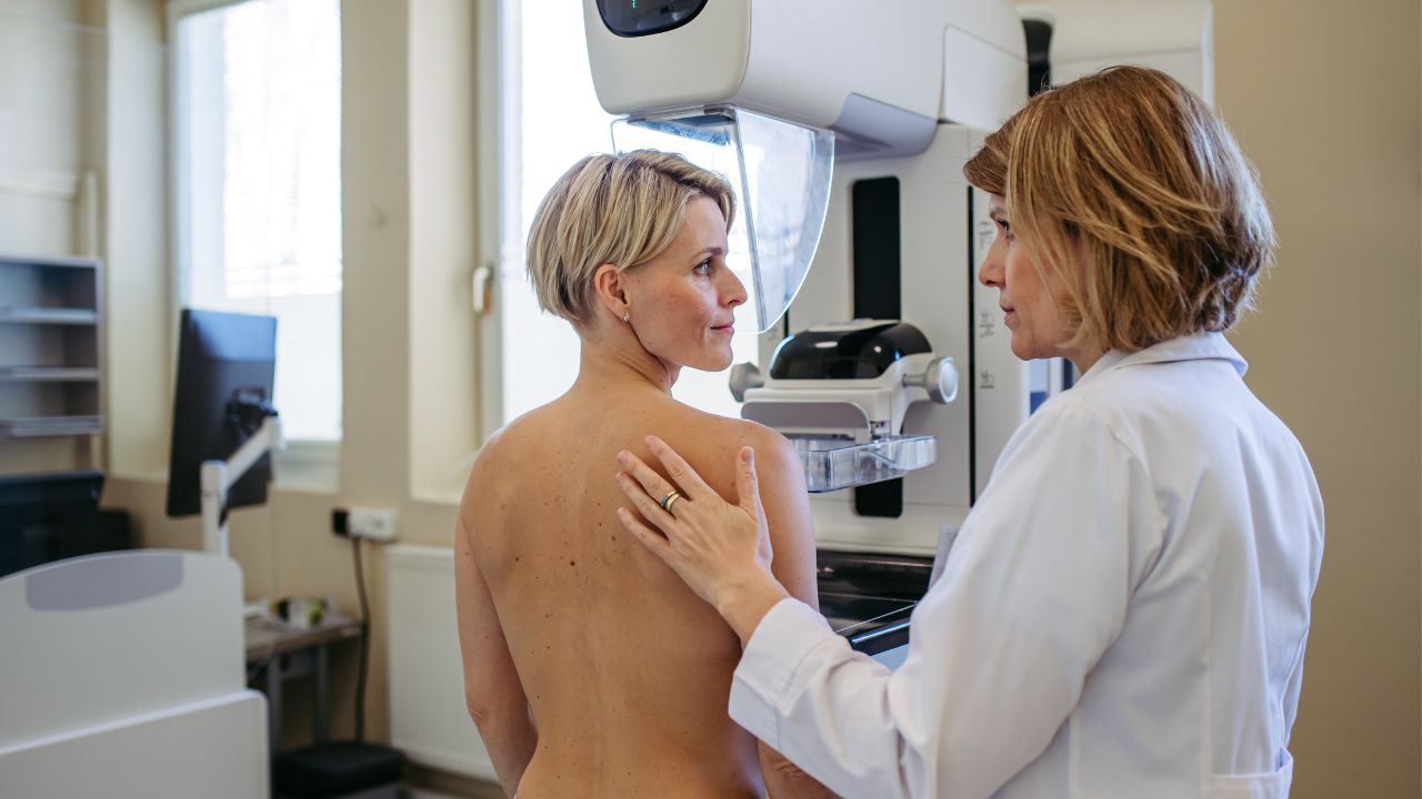 Vrouw tijdens een borstonderzoek met een zorgverlener en mammografieapparaat