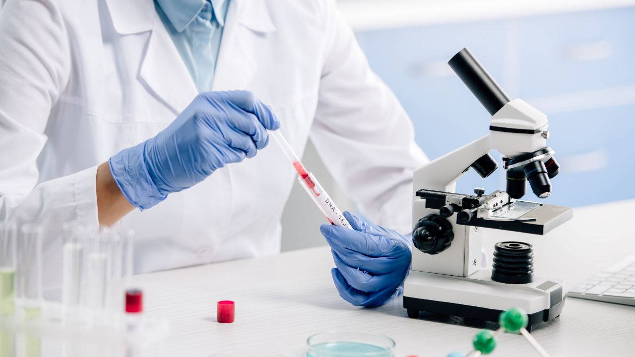 Onderzoeker voert genetische test uit in een laboratorium met een bloedstaal en microscoop