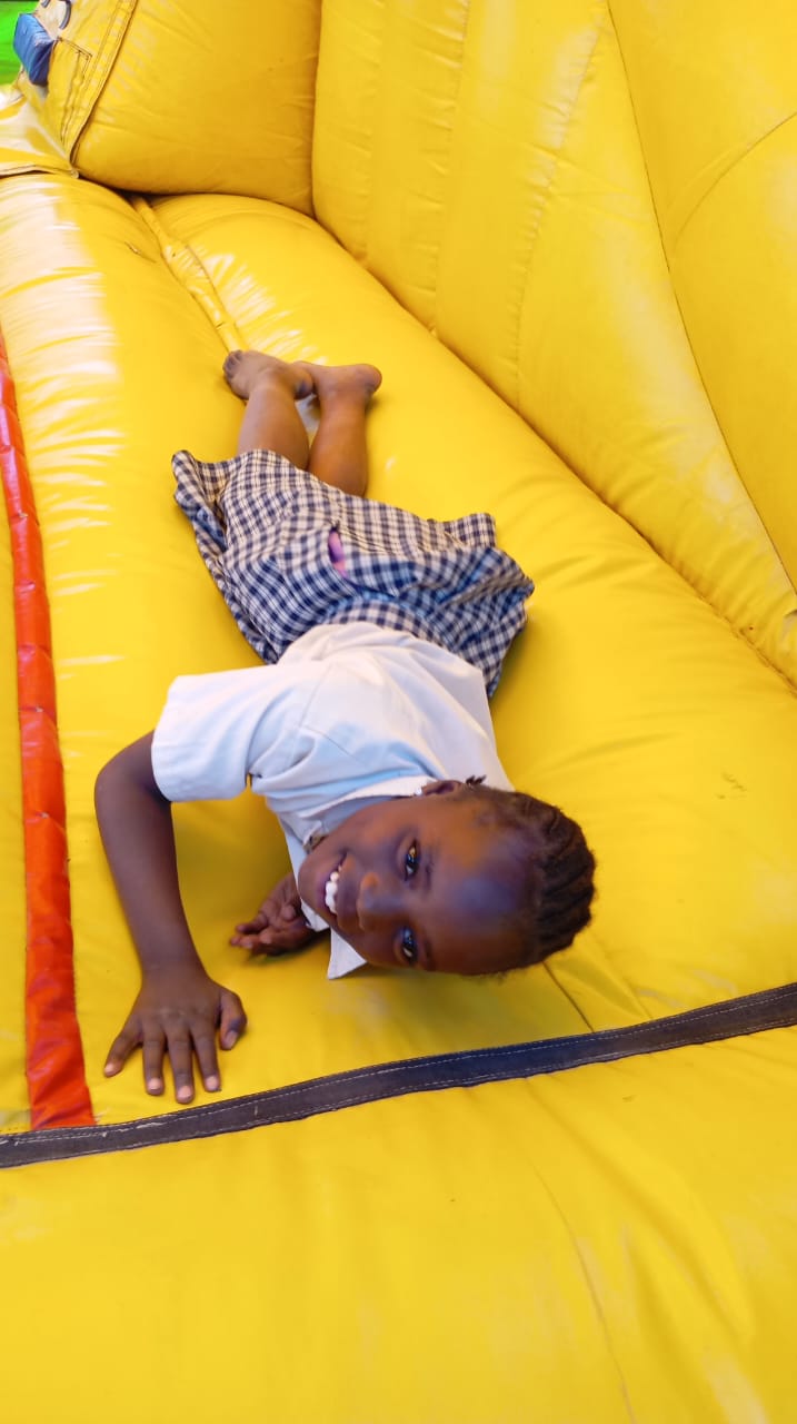 Smiling child lying on a bright yellow inflatable play structure.