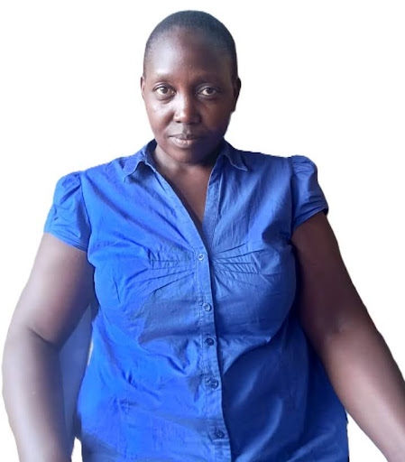 Portrait of a woman wearing a blue short-sleeve button-up shirt sitting against a white background.