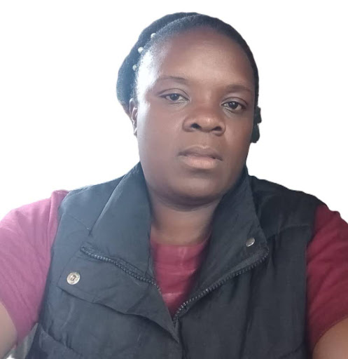 Portrait of a woman with braided hair wearing a black vest over a maroon shirt against a plain background.