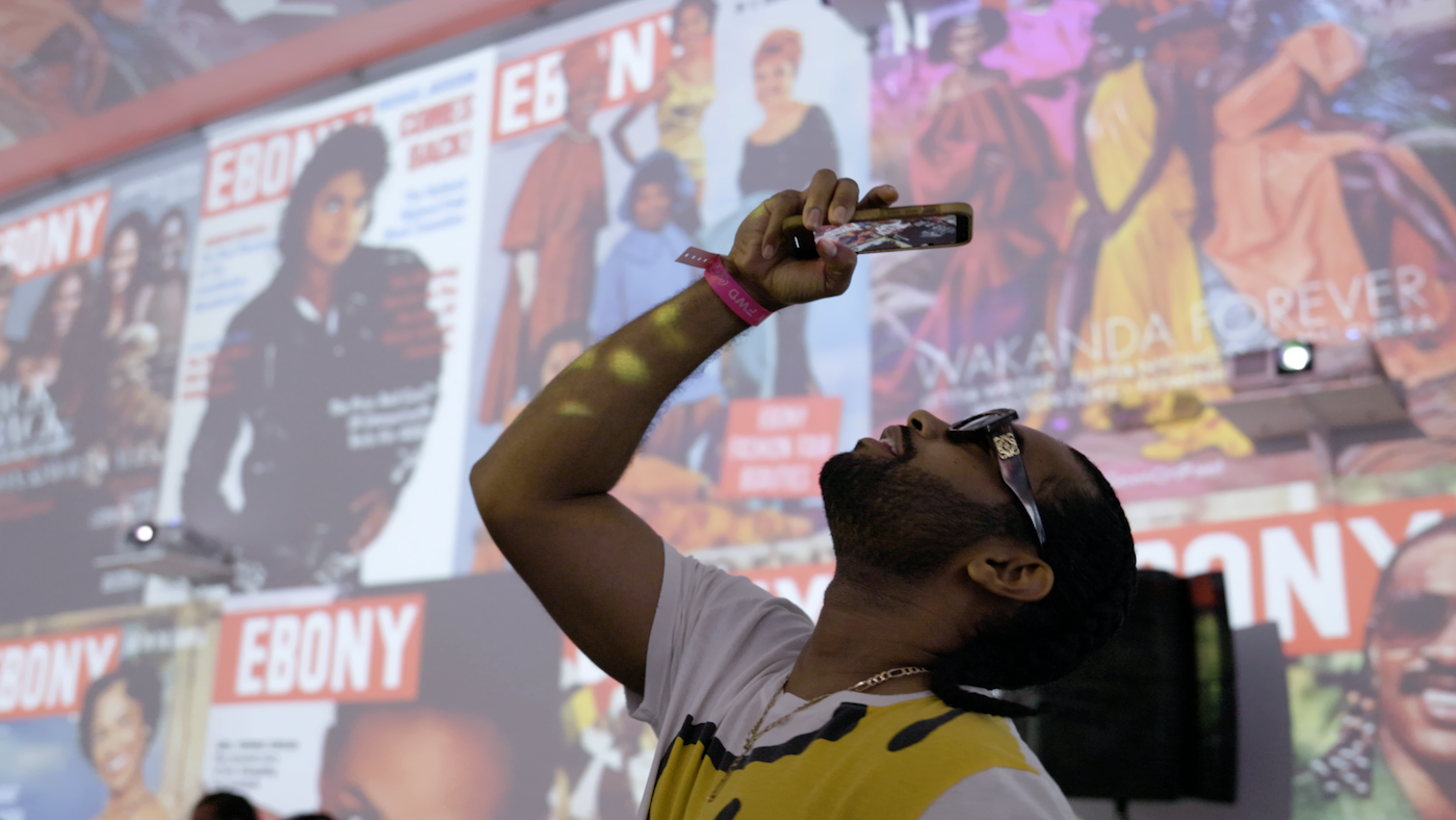 A man taking a photo at an Ebony magazine event.