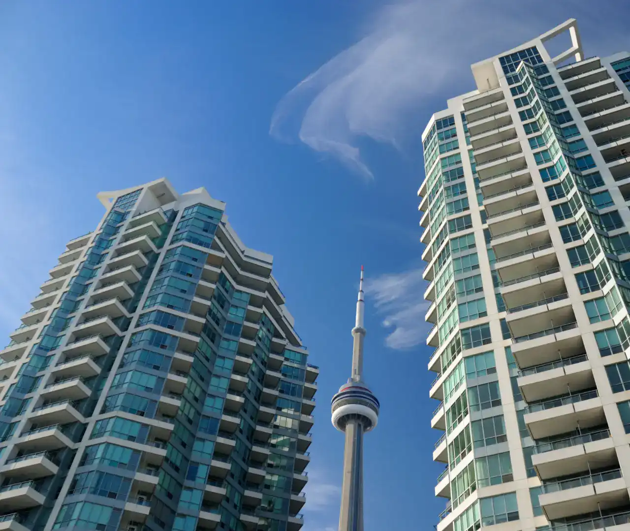 Outdoor image of 2 condominiums with CN Tower showing from a distance between them.