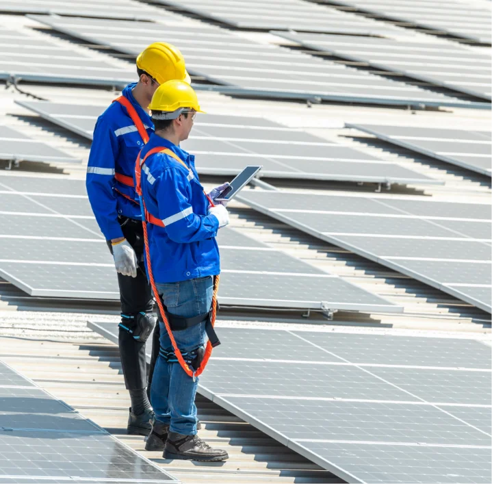 Two solar technicians standing on mounted panels discussing installation at a commercial site in Indiana