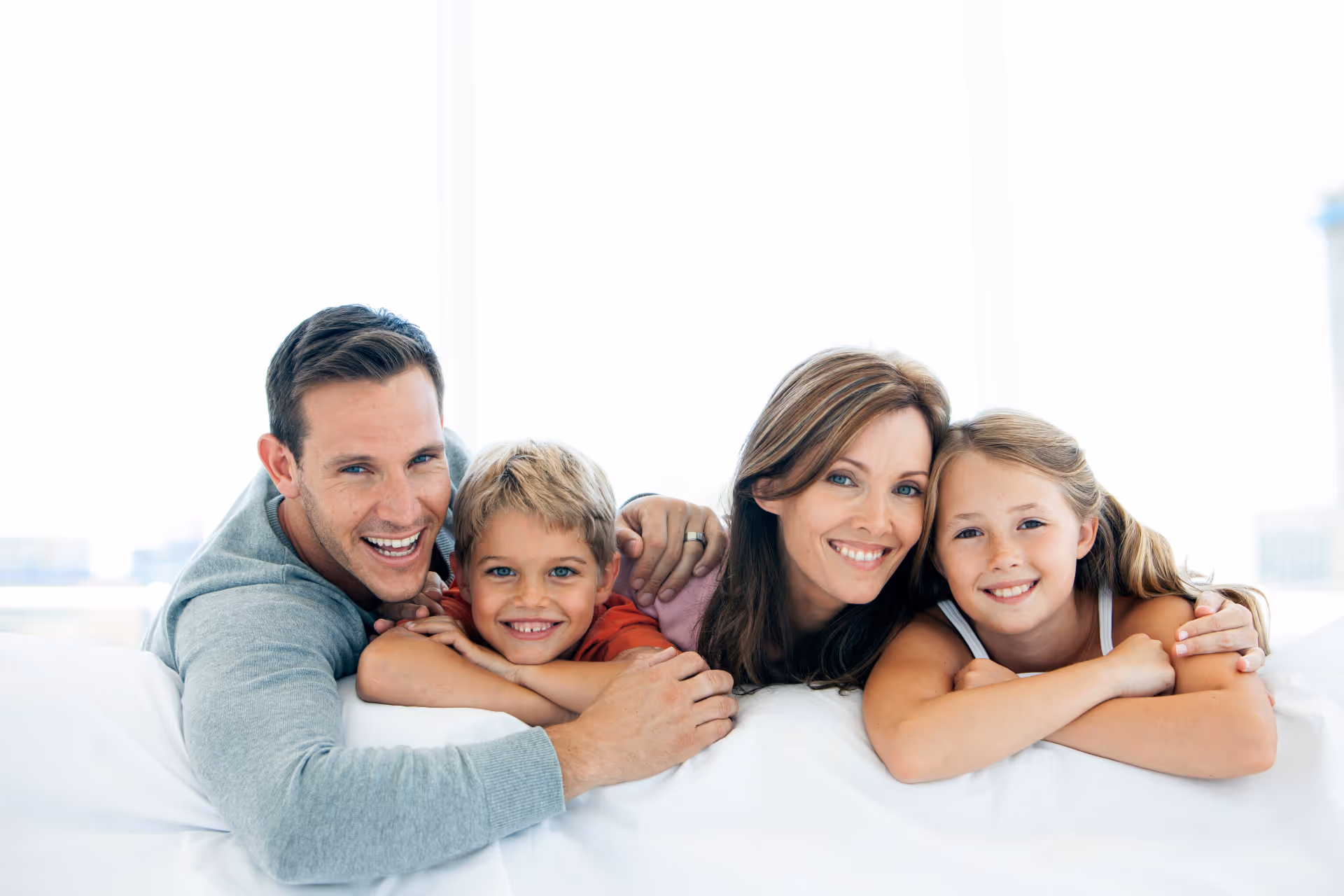 happy family with two children lying down and looking at camera in Brownstown Township