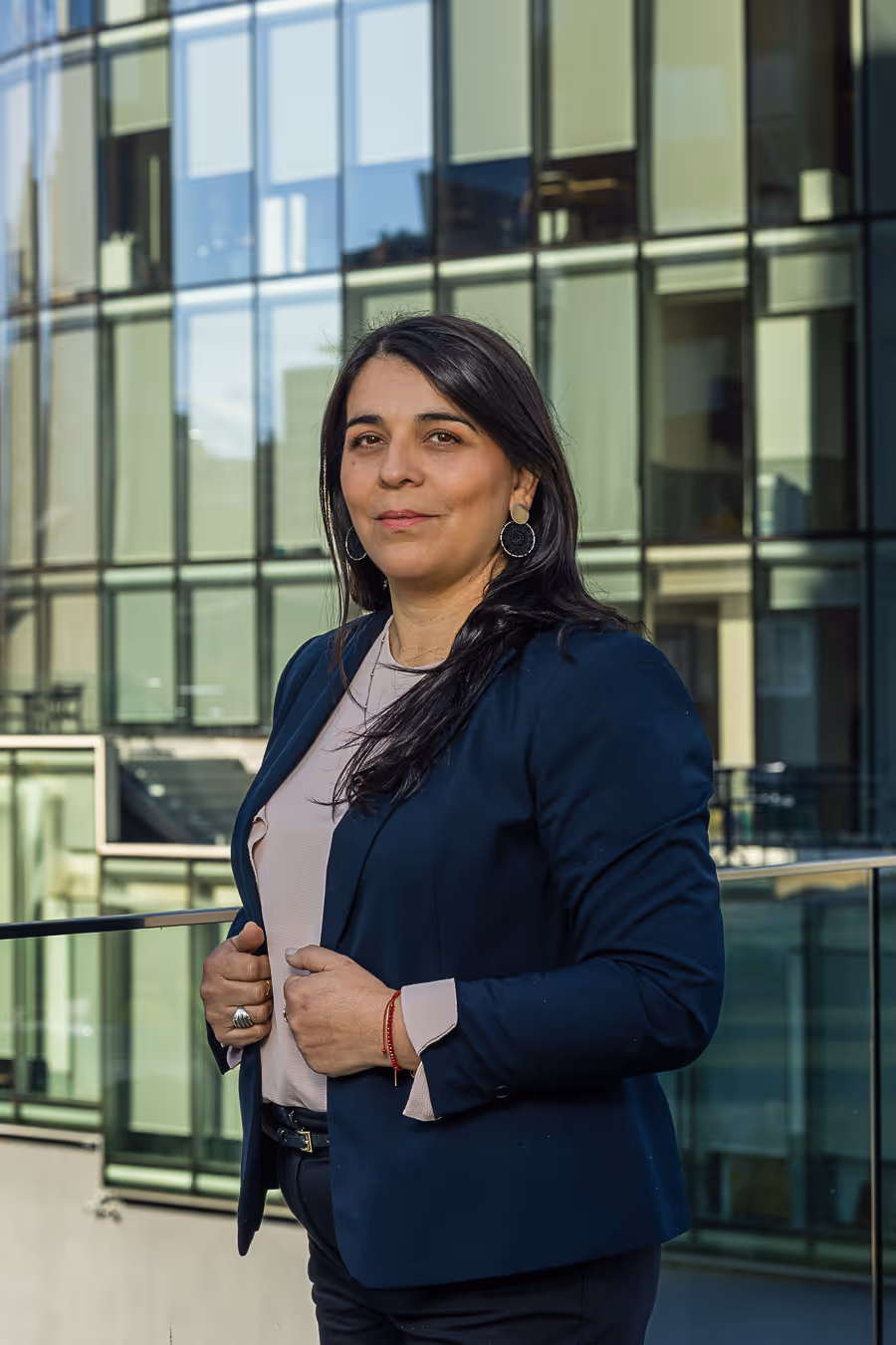 Retrato de Mariela Parada con edificio de vidrio y fondo natural