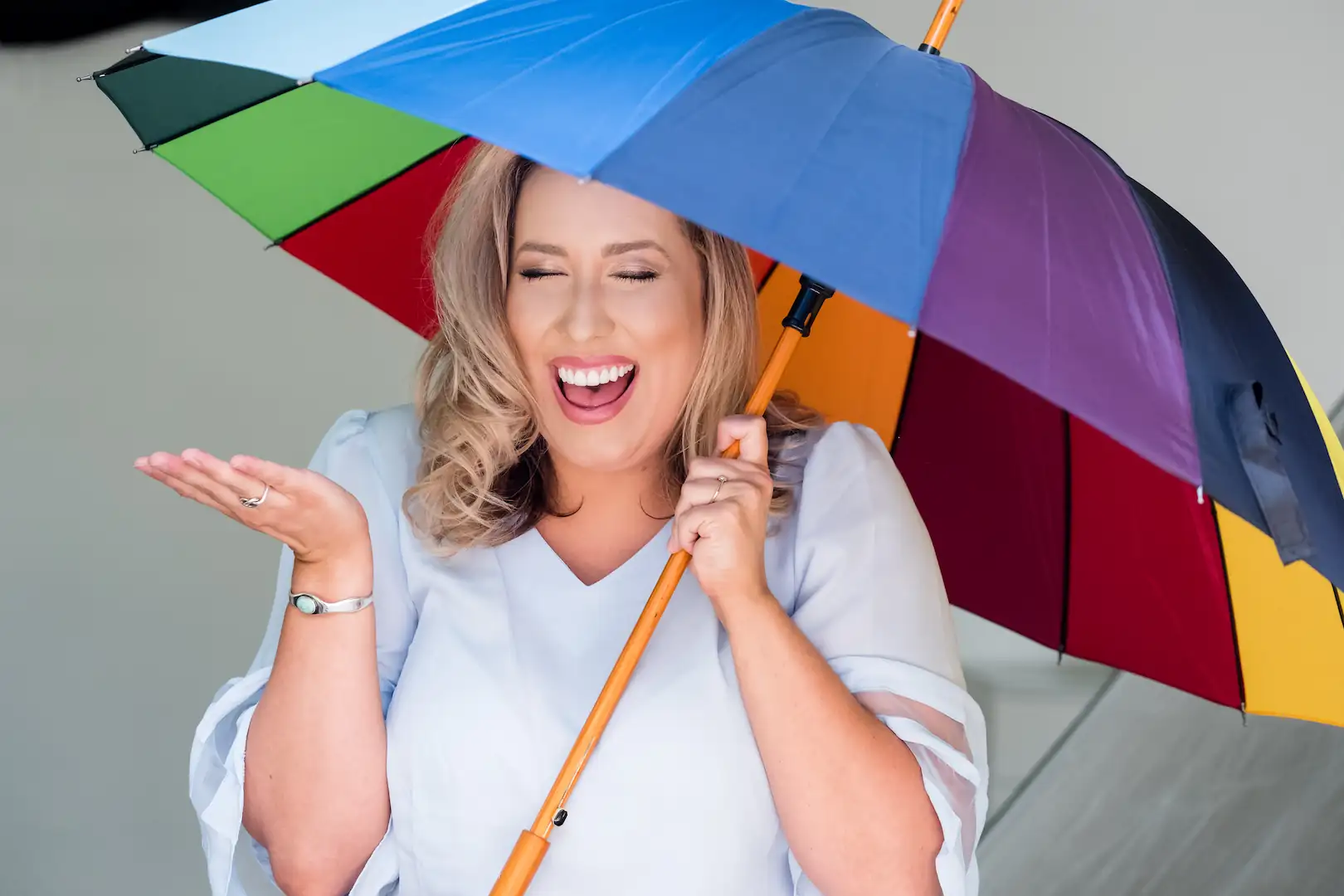 Smiling woman holding a colorful umbrella, showing off her bright, confident smile.