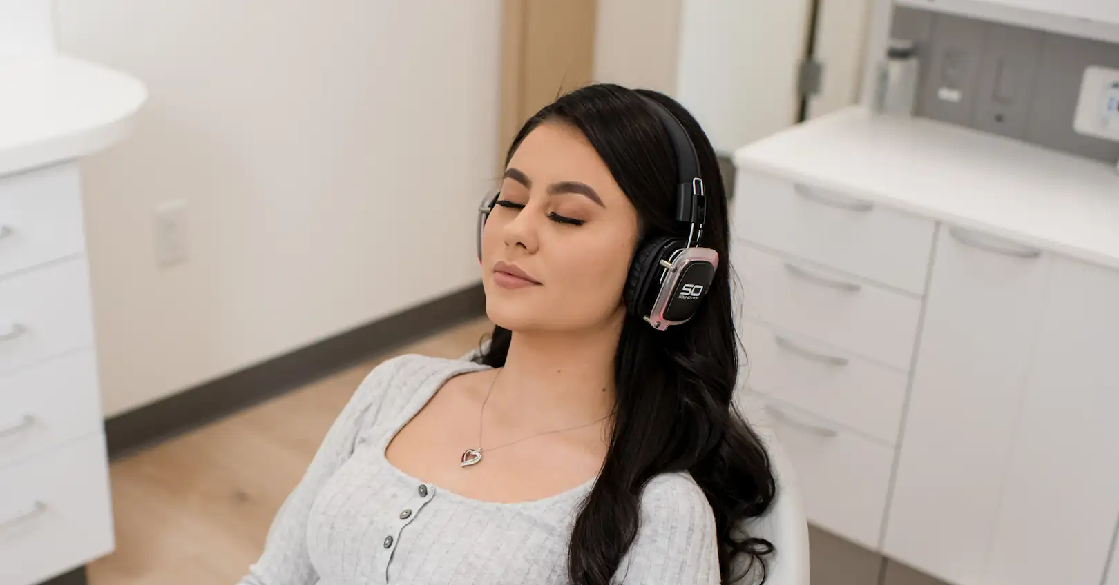 Woman relaxing in a dental chair with headphones on, looking calm and comfortable during her sedation dentistry visit.