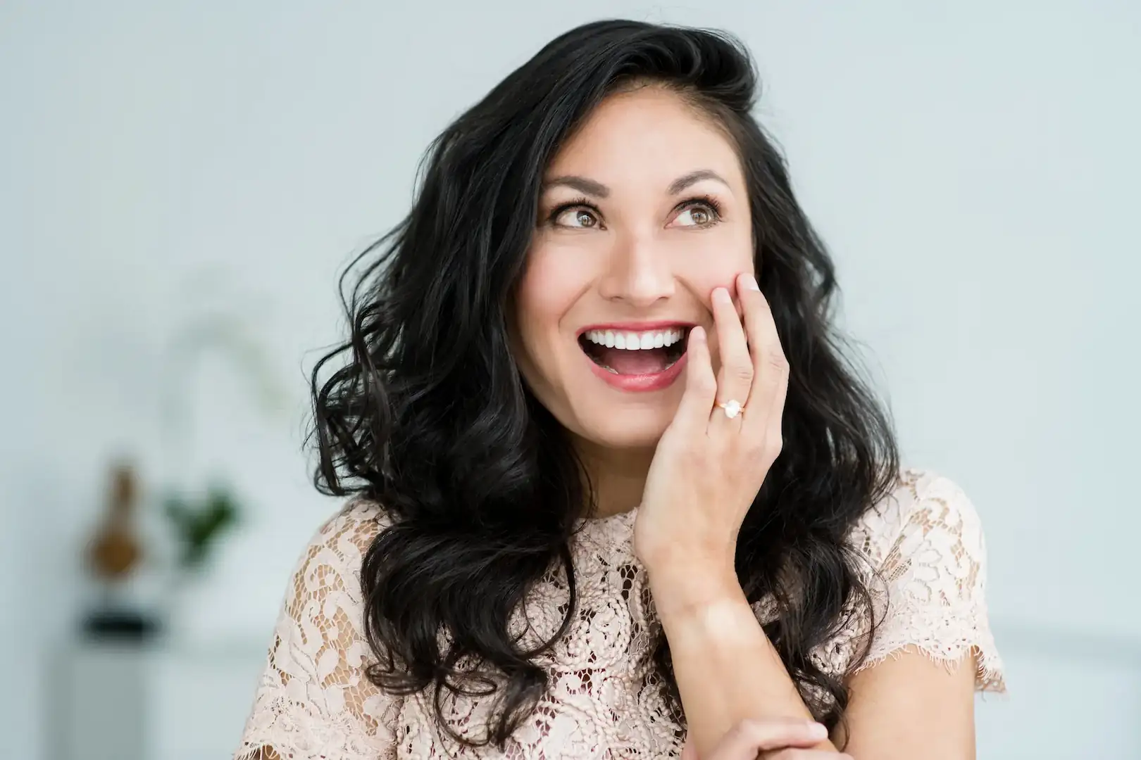 Woman smiling brightly with her hand on her cheek, showing a healthy, white smile.