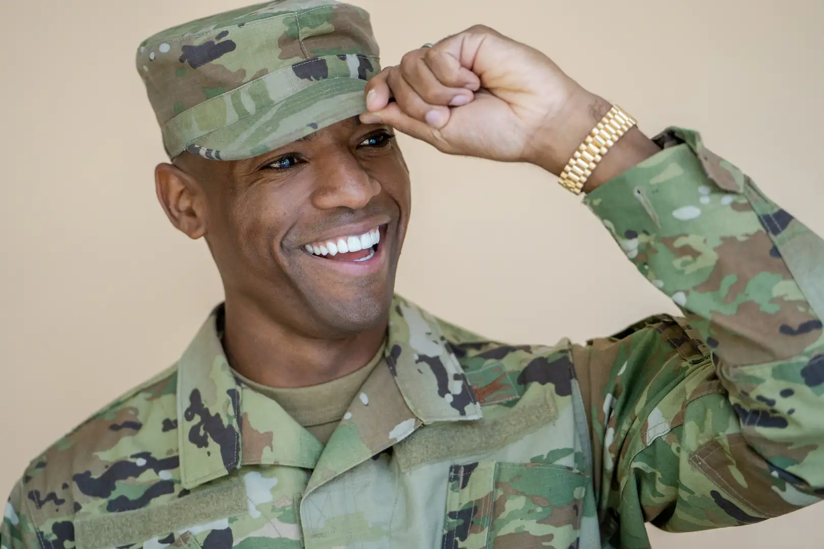 Smiling Espire patient in military uniform adjusting his cap, showing a bright and confident smile.