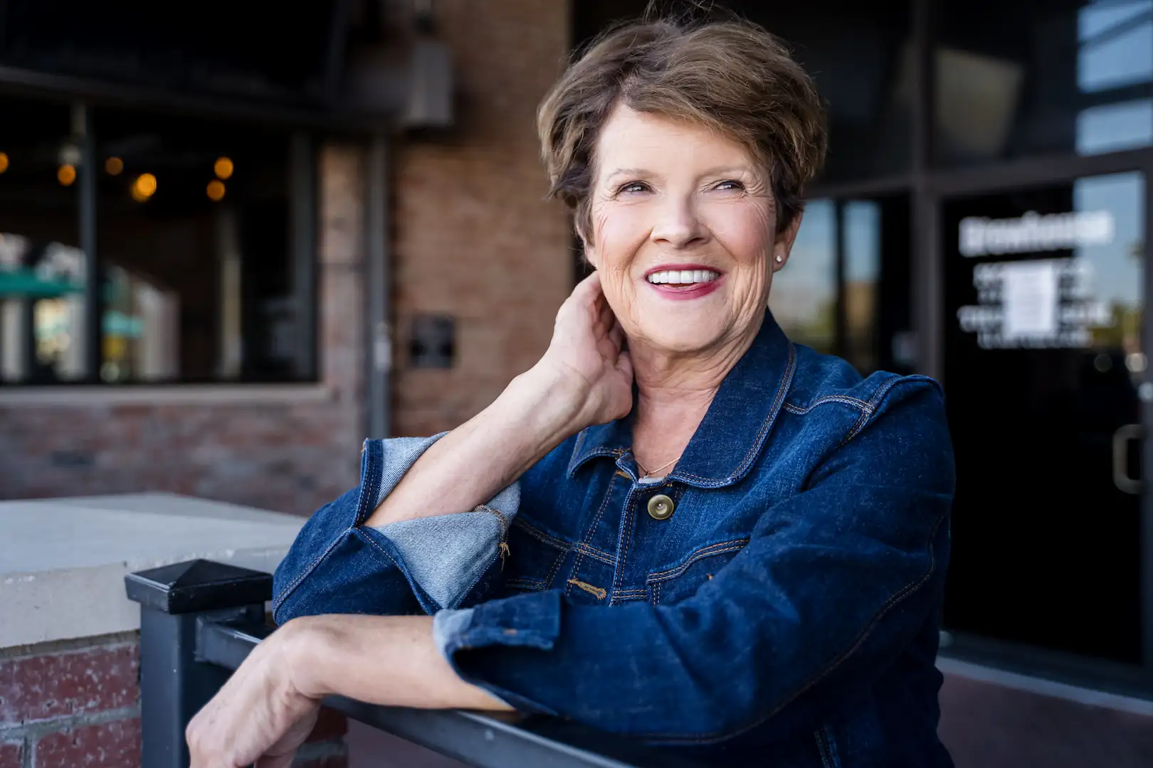 Espire patient smiling warmly while sitting outside in a denim jacket, displaying a healthy and confident smile.