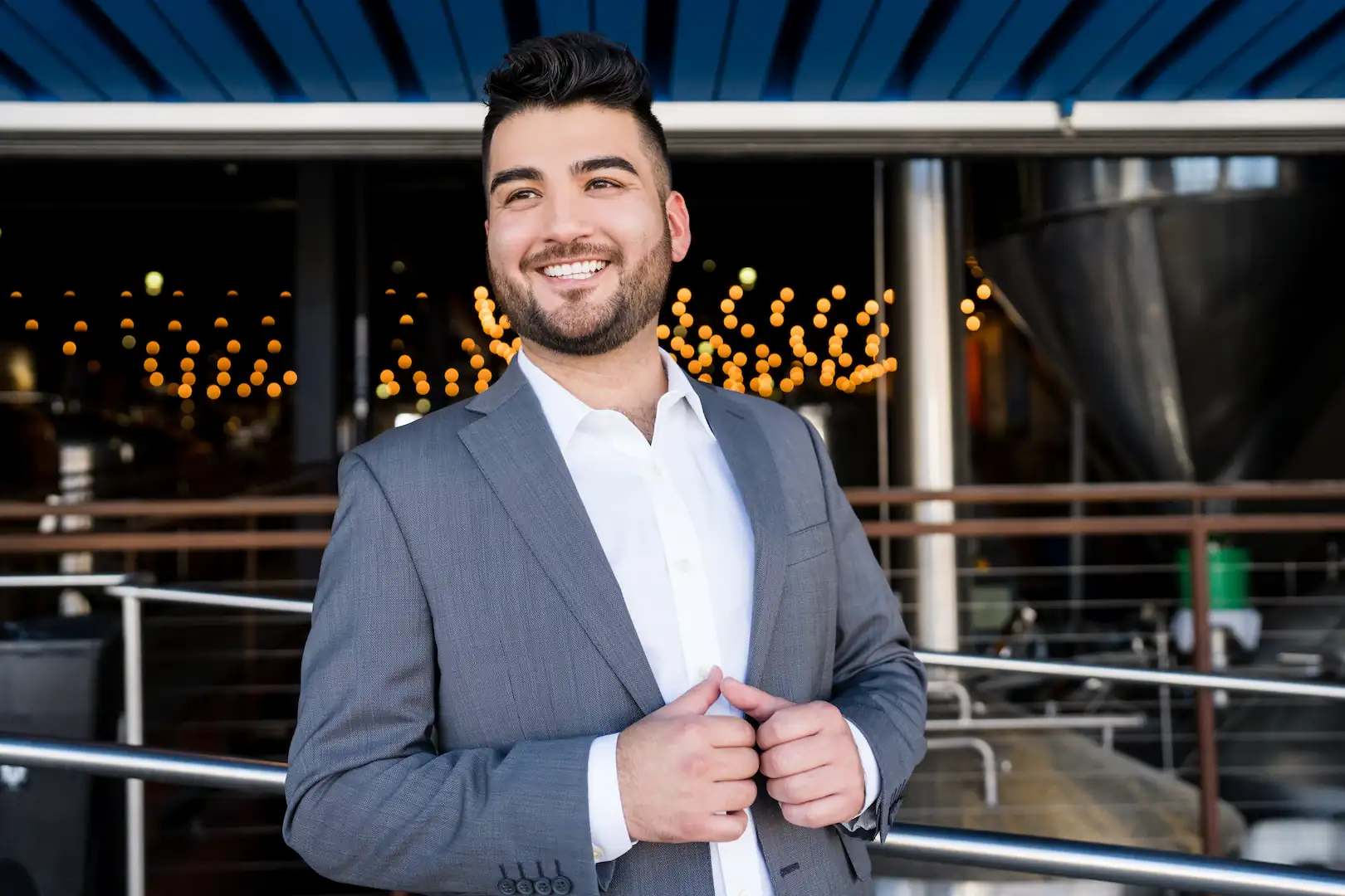 Confident Espire patient standing outside in a suit, smiling brightly with warm ambient lights in the background.