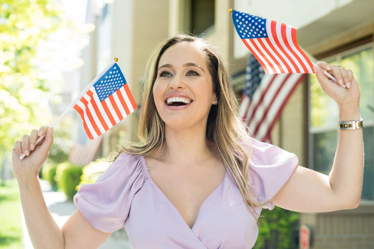 San Diego woman showing off dream smile after seeing cosmetic dentist in La Mesa holding American flags