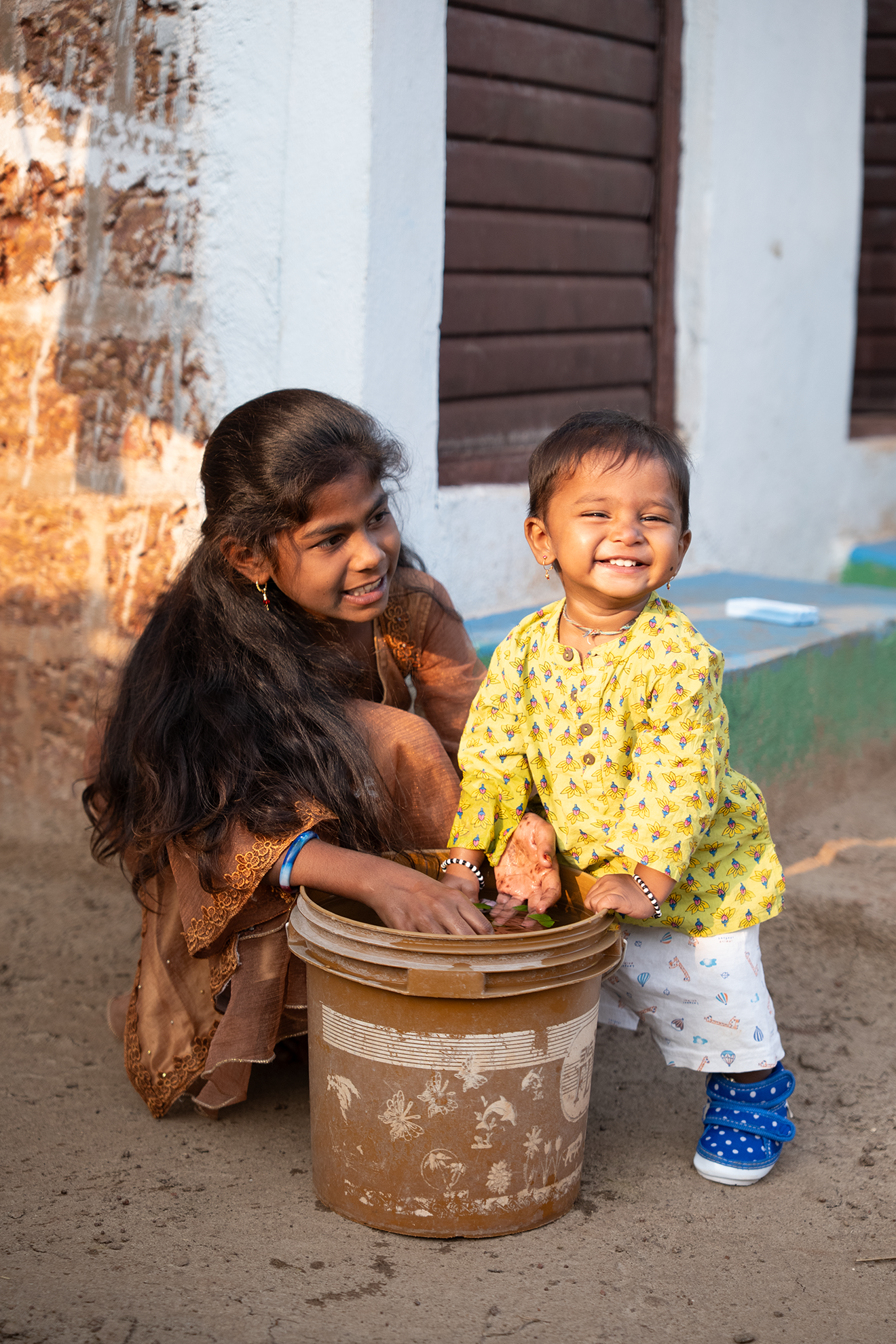 two girls playing with a bucket 
