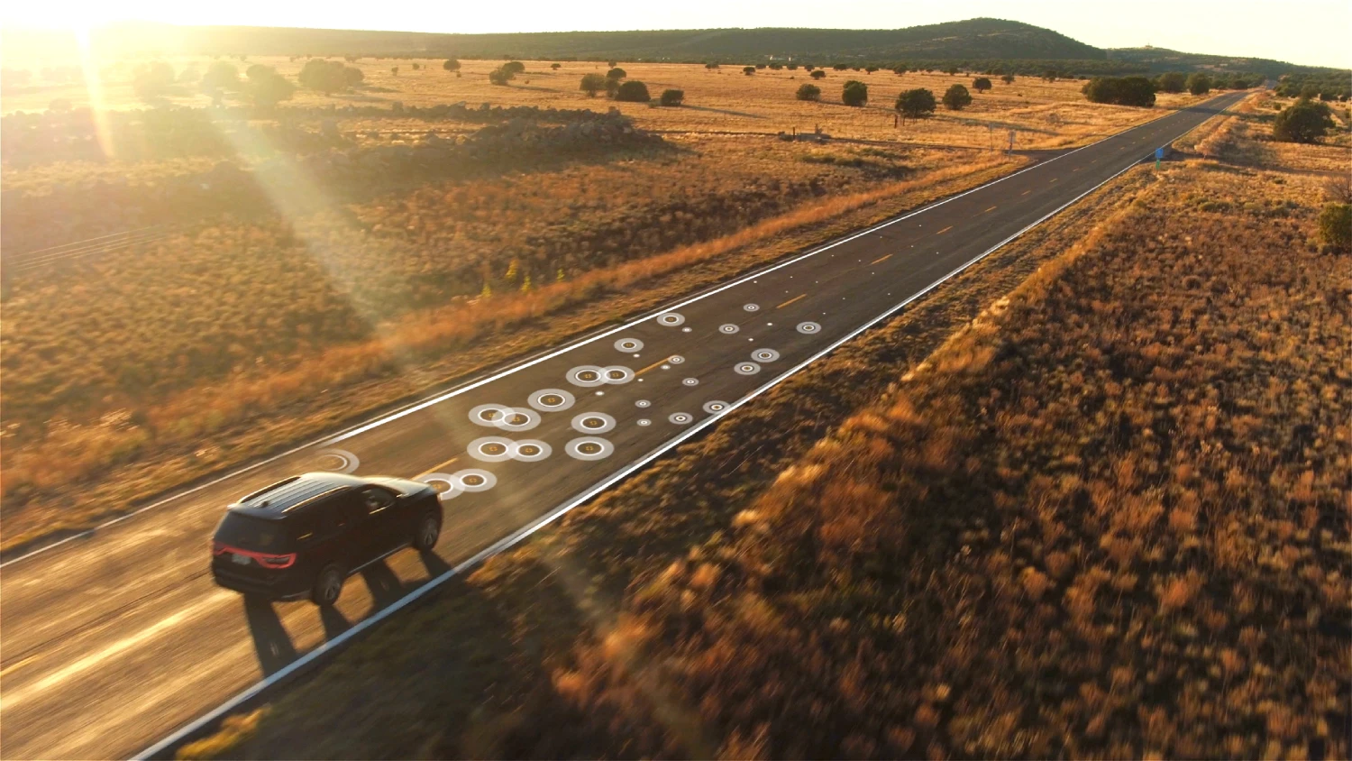 Aerial still of car driving on road with Sentric branded video overlay