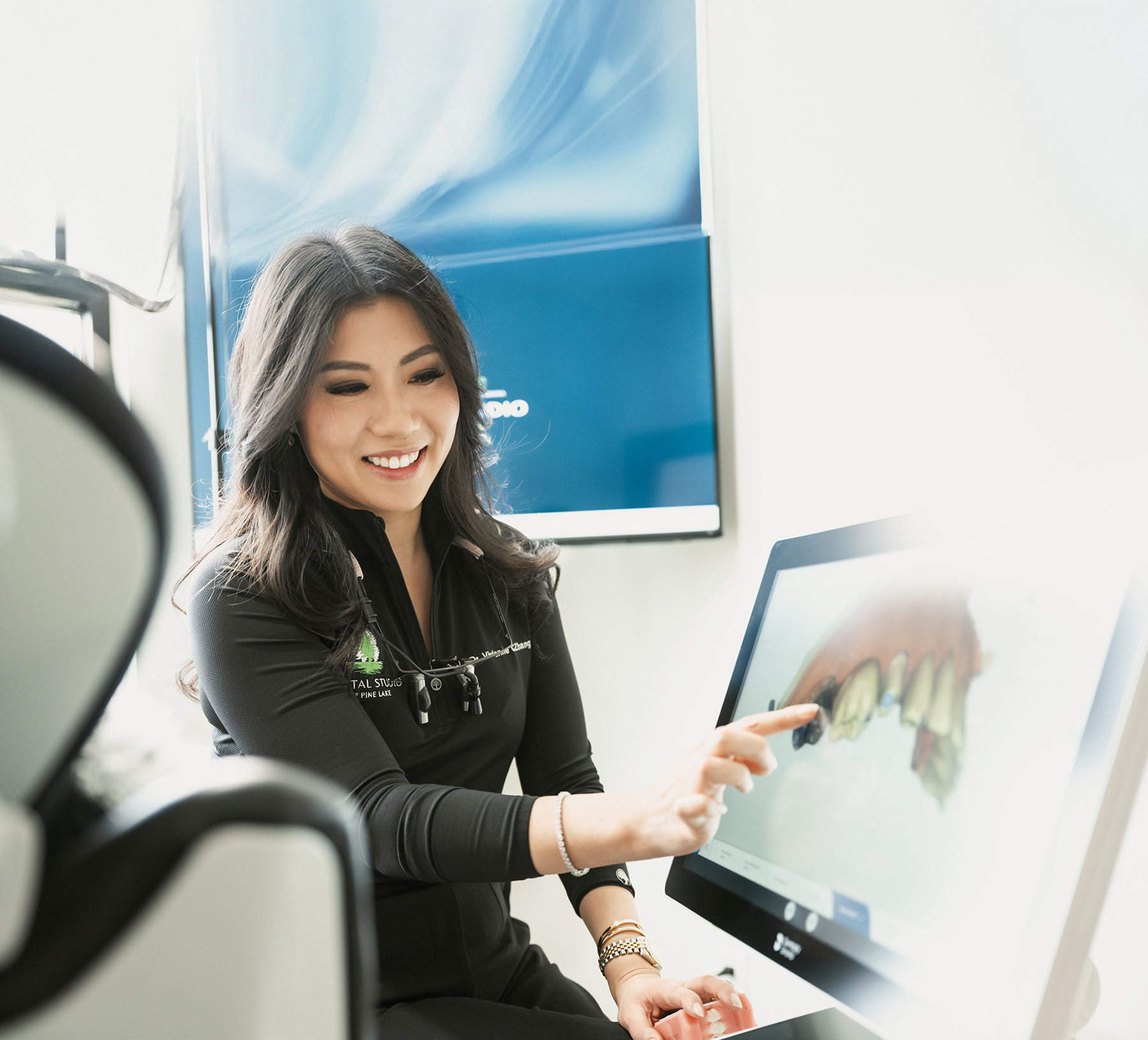 Dentist smiling while pointing at a computer screen