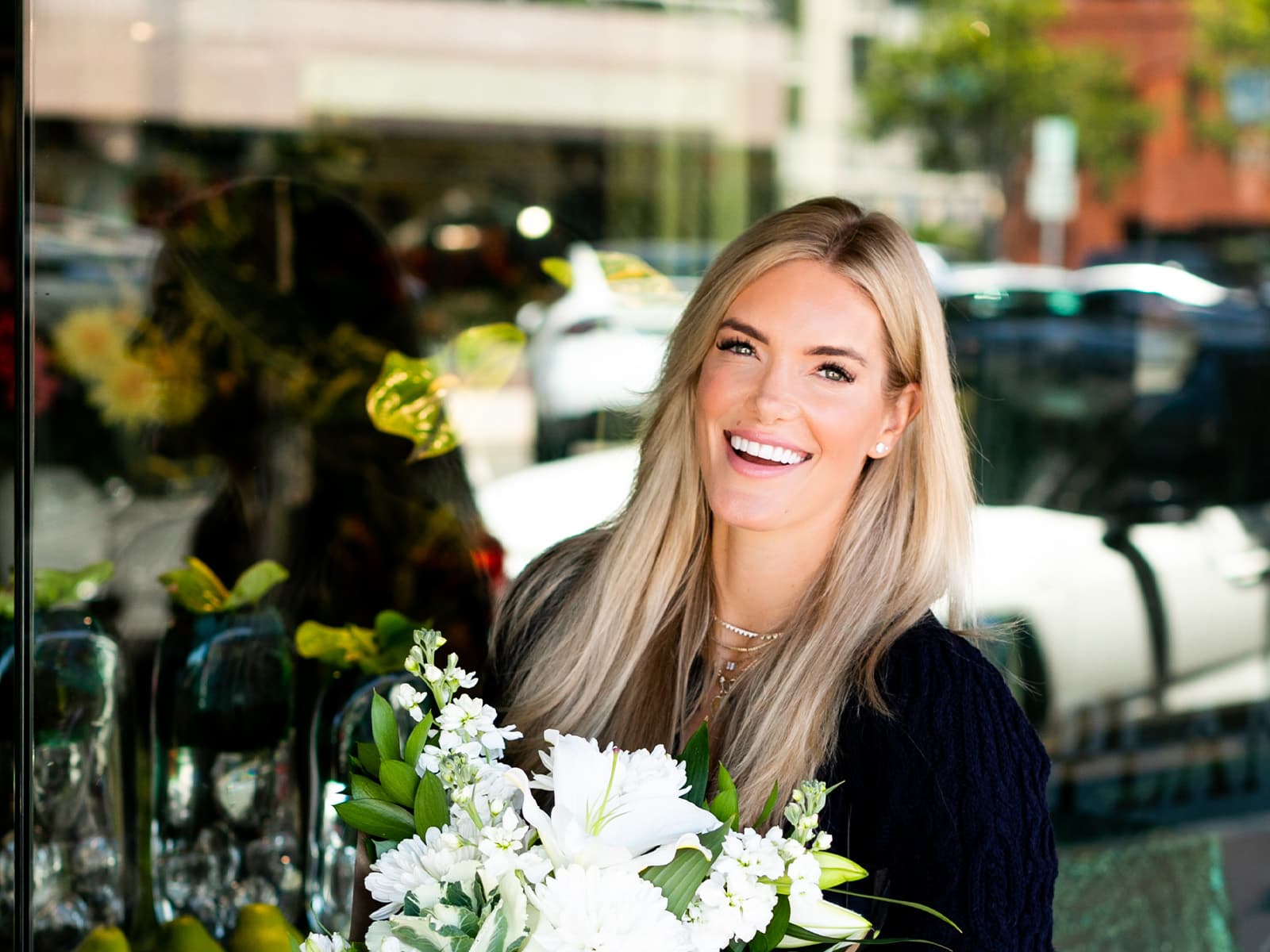 Ashley, an Espire Dental patient is showing off her bright smile while holding a bouquet of white flowers