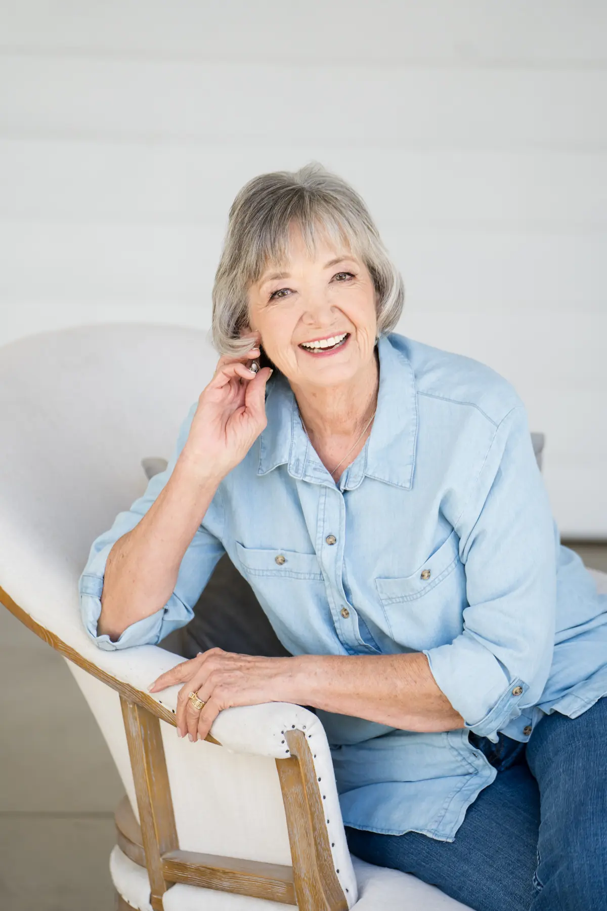 Smiling senior woman in a light denim shirt sitting comfortably and showing her healthy smile after dental care at Espire Dental.