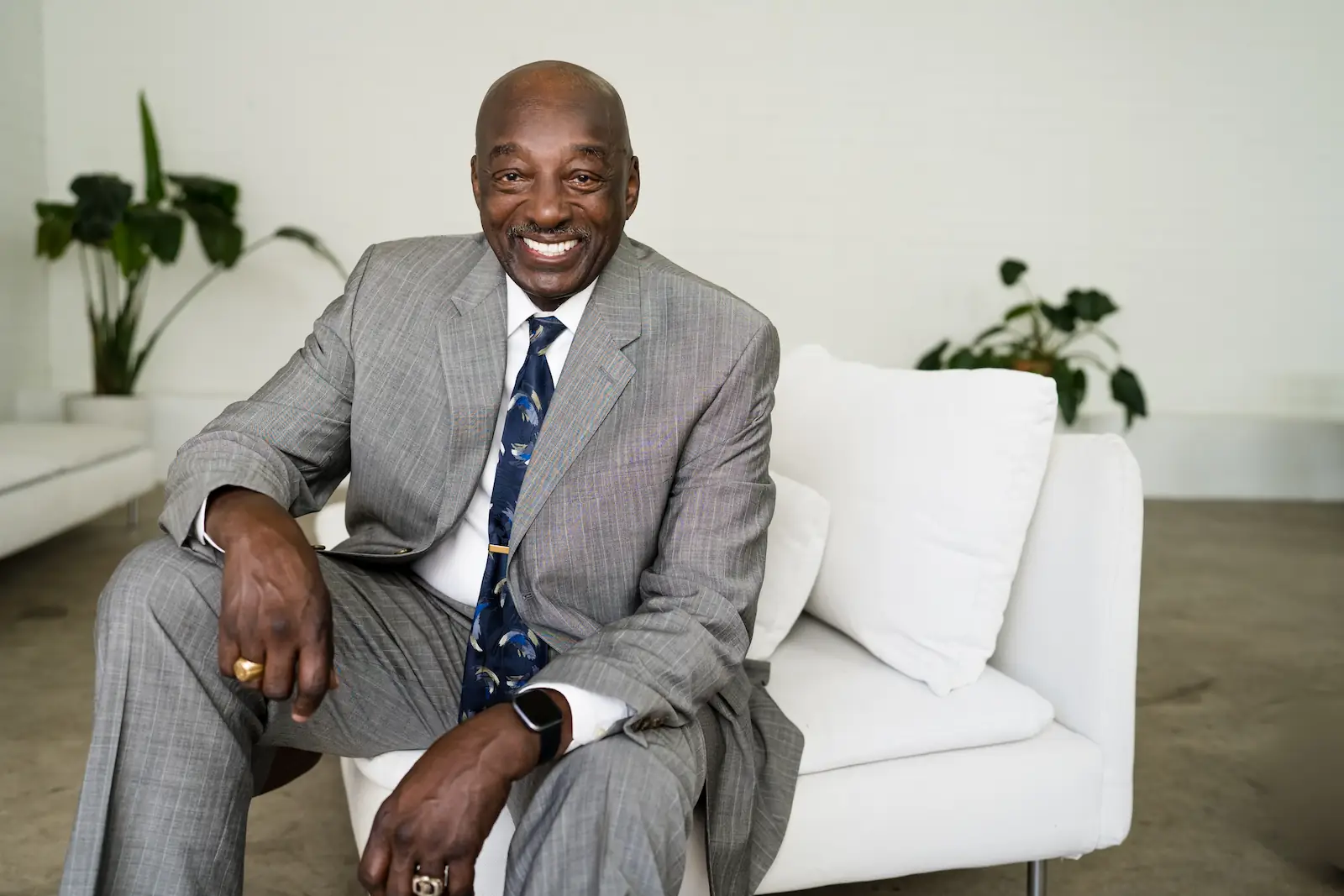 Older man in a gray suit smiling confidently after senior dental care at Espire Dental.