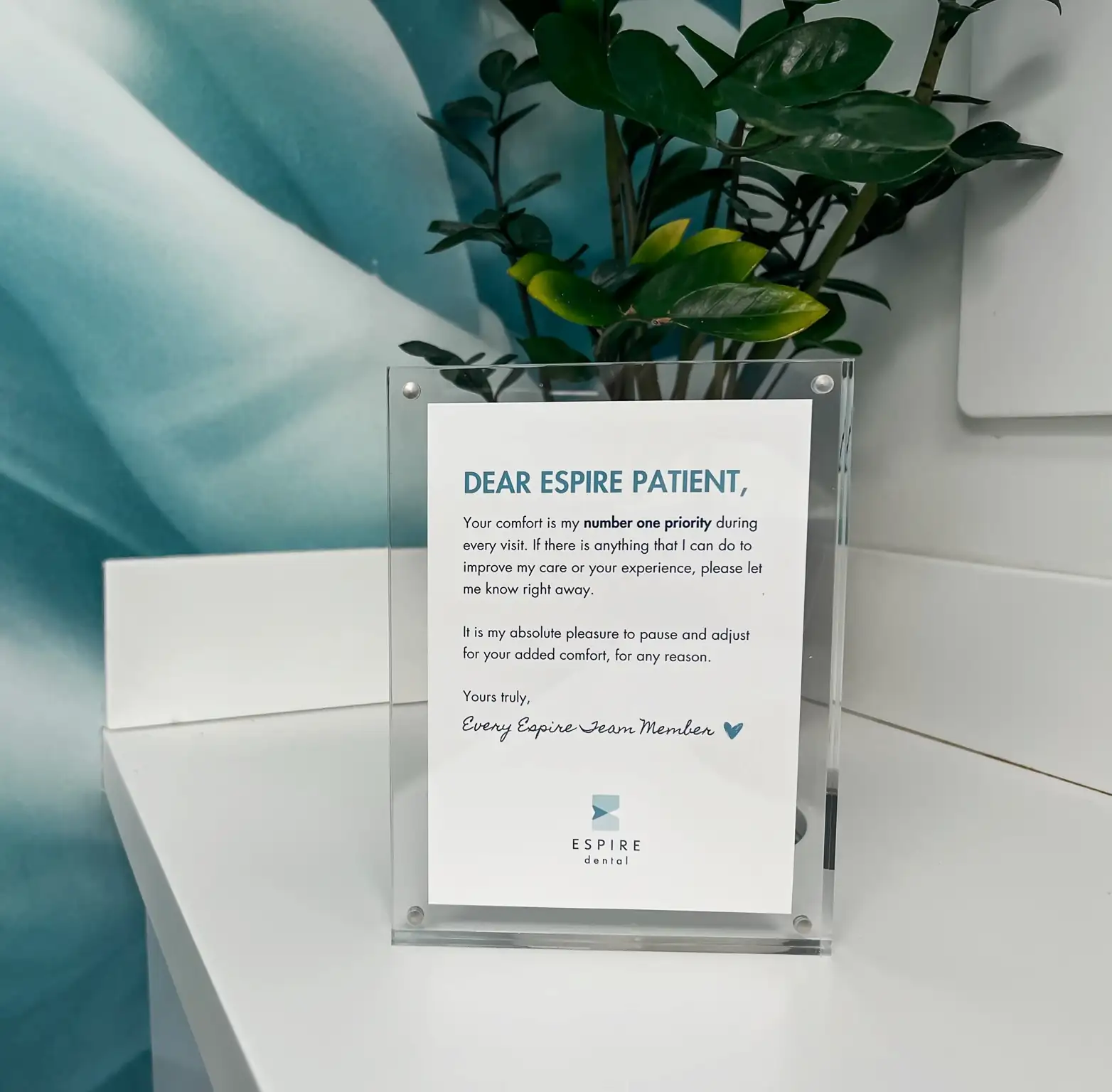 Image of a small sign that says "Your comfort is my number one priority during every visit. If there is anything that I can do to improve my care or your experience, please let me know right away. It is my absolute pleasure to pause and adjust for your added comfort, for any reason."