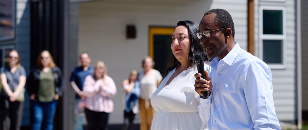 A man and a woman are standing in front of a group of people.