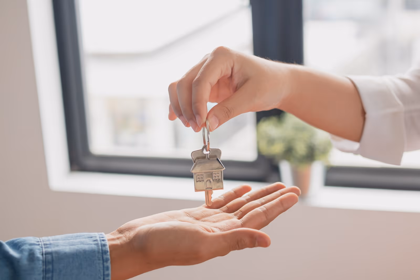 A person handing a house key to another person.